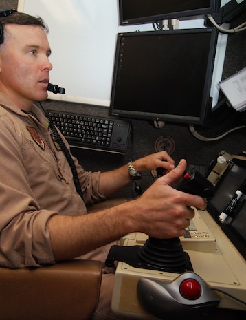 JOINT BASE BALAD, Iraq -- Maj. John Chesser operates the controls of an MQ-9 Reaper cockpit during a demonstration here Aug. 1. The Reaper is an unmanned aerial system designed to hunt down and kill enemy targets, and its long loiter time and 3,750-pound payload offer ground commanders flexibility, persistent stare and persistent strike capabilities. Major Chesser, a Reaper pilot with the 46th Expeditionary Reconnaissance and Attack Squadron here, is deployed from Creech Air Force Base, Nev. (U.S. Air Force photo/Staff Sgt. Don Branum)
