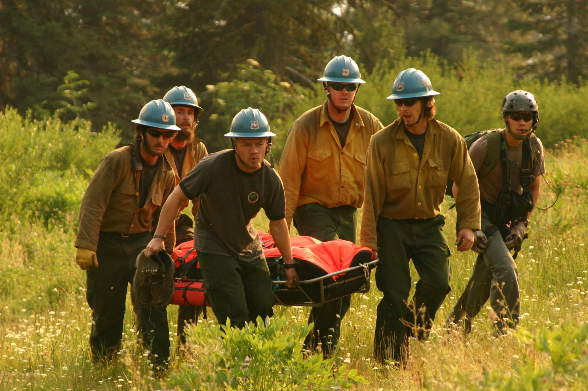 Staff Sgt. Darren Pon (right), pararescueman from the 131st Rescue Squadron, accompanies a Shasta, California-based firefighting crew carrying an injured firefighter to an awaiting HH-60G Pave Hawk northwest of Redding, Calif., July 31. While battling the Iron Complex Wildland Fire, the firefighter fell and suffered a concussion. The 129th Rescue Wing aircrew and pararescuemen landed in rugged terrain at approximately 6,000 feet to rescue the firefighter, and subsequently medevaced him to Mercy Medical Center in Redding. (U.S. Air Force photo by Tech. Sgt. Brock Woodward)