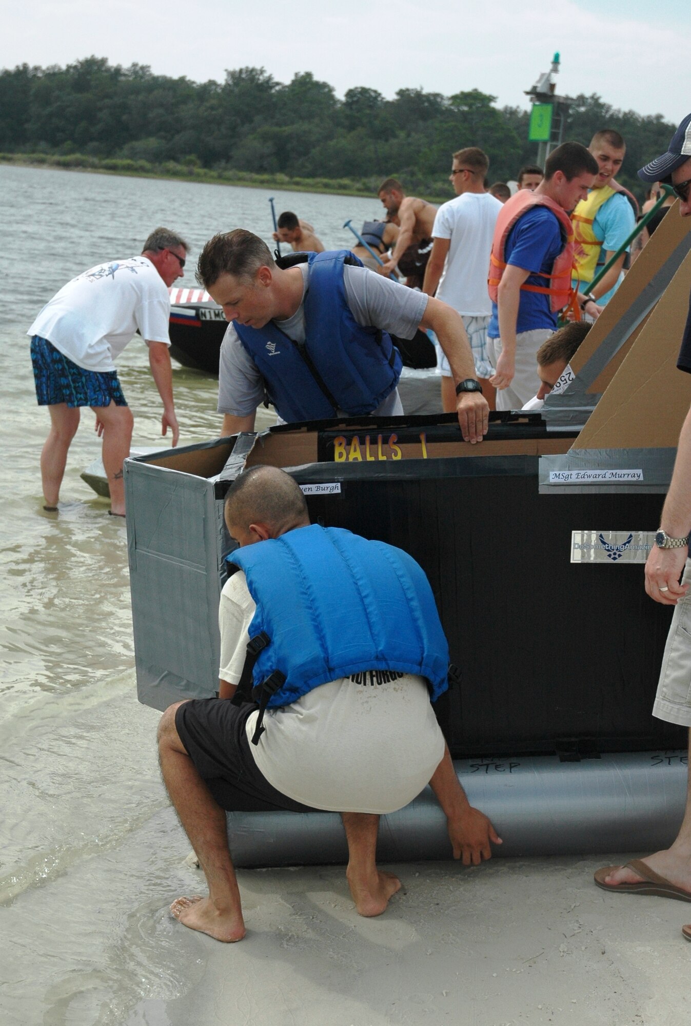 Lt. Col. Steven Burgh, 325th Operations Support Squadron commander and Master Sgt. Edward Murray, 325th OSS first sergeant, carry their watercraft to the water's edge at the start of the 2008 325th OSS Regatta Boat Race held July 25 at the Bonita Bay Recreation Center. Hand-crafted cardboard boats were built by flights and sections within the squadron, and were tested for speed and seaworthiness during the competitive squadron event.