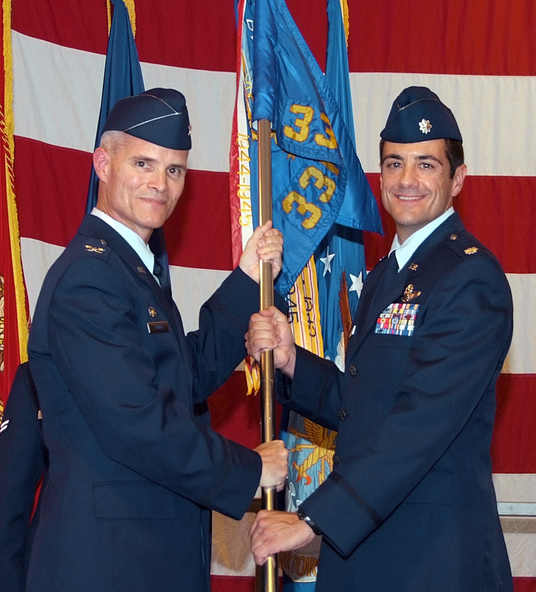 Lt Col. Robert Capozzella accepts command of the 33rd Flying Training Squadron from Col. Douglas Troyer, 71st Operations Group commander, during a change of command ceremony Aug. 1 in Hangar 170 at Vance AFB, Okla.