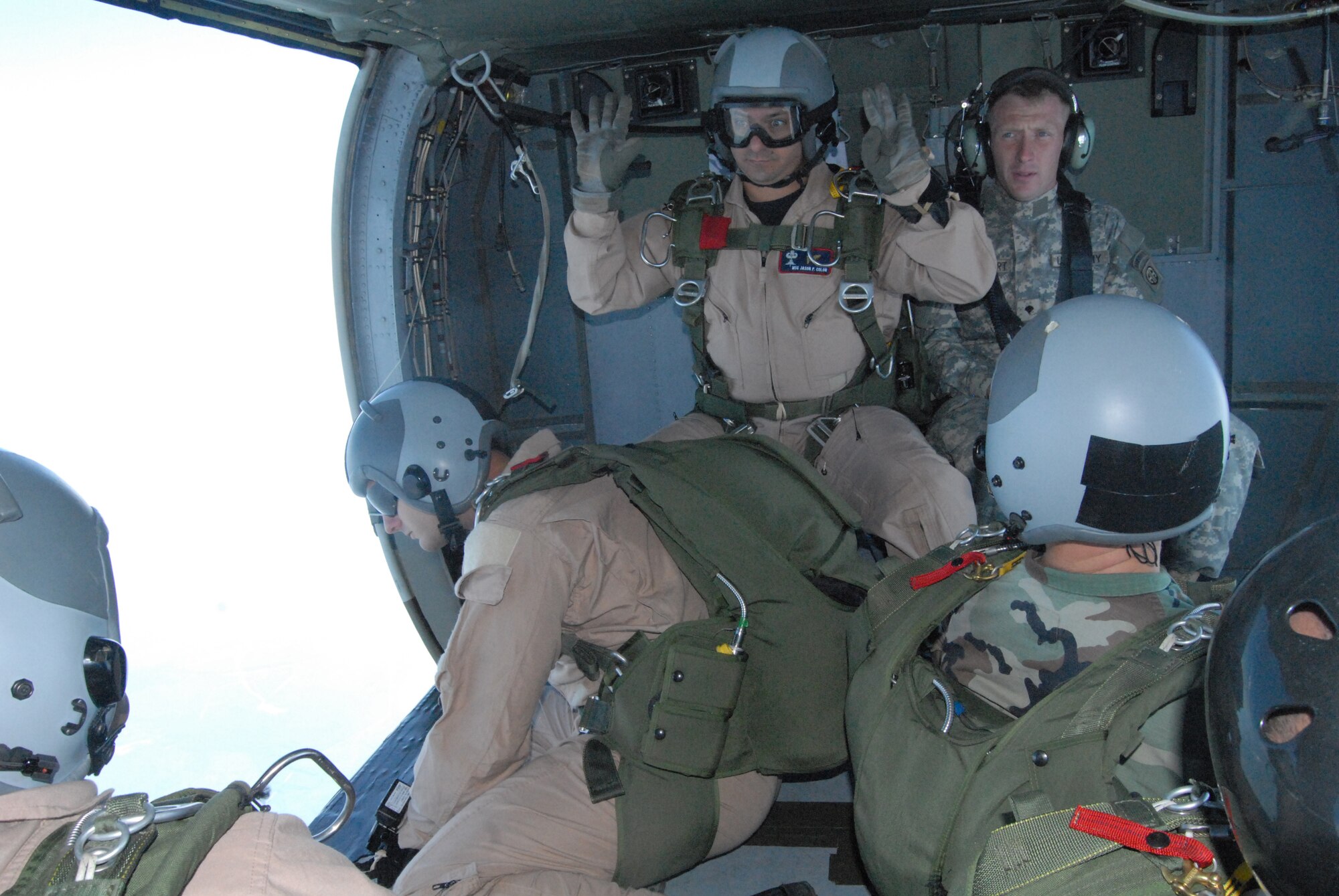 Master Sgt. Jason Colon, 18th Weather Squadron first sergeant, gives a signal to four Airmen waiting to execute a High Altitude, Low Opening jump over Luzon Drop Zone July 16. Sergeant Colon served as jumpmaster and was giving non-verbal cues to his jumpers due to the noise made by the UH-60 Black Hawk helicopter. (U.S. Air Force Photo by 2nd Lt. Chris Hoyler)