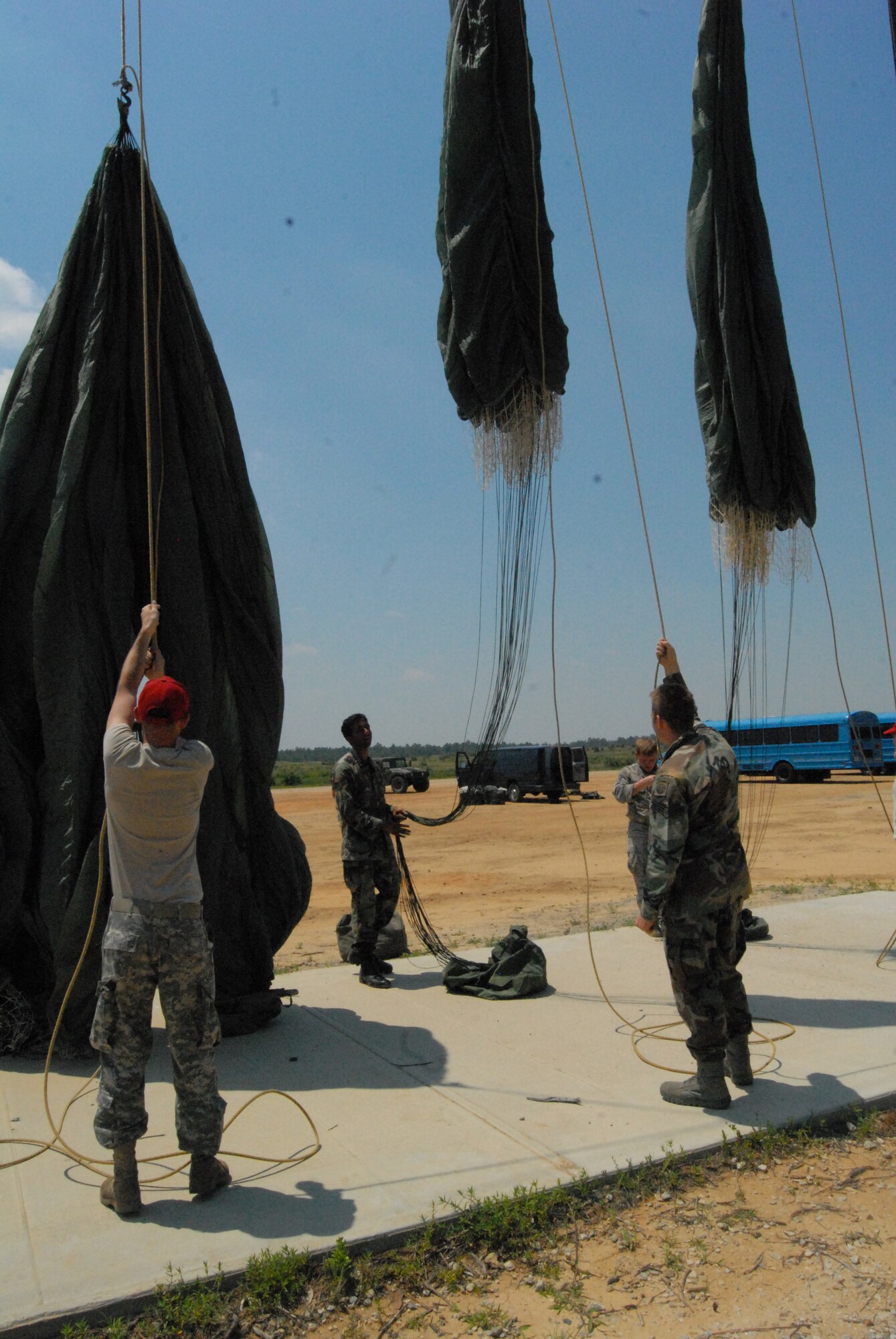 Airmen from the 93rd Air Ground Operations Wing and parachute riggers from Fort Bragg do a “chute shake out” after one of the static line jumps at Luzon Drop Zone July 16. The shake out makes sure that all debris that may have ended up in the parachute during the jump is out before the riggers re-pack it for the next jump. (U.S. Air Force Photo by 2nd Lt. Chris Hoyler)