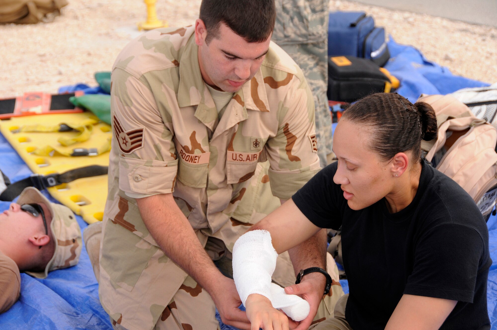 Staff Sgt. Mathew Rooney, 34th Expeditionary Bomb Squadron, an independent medical duty technician from Ellsworth Air Force Base, S.D., dresses a simulated third-degree burn on the arm of Staff Sgt. Jackie Carr, 379th Expeditionary Force Support Squadron, during a Major Accident Response Exercise in Southwest Asia July 28.  The objective was to test key personnels' response to a major accident.  Emphasized areas were emergency response operations, accountability of personnel, mortuary services and higher headquarters reporting procedures. Sergeant Carr is deployed from Davis-Monthan Air Force Base, Ariz. (U.S. Air Force photo by Tech. Sgt. Michael Boquette)