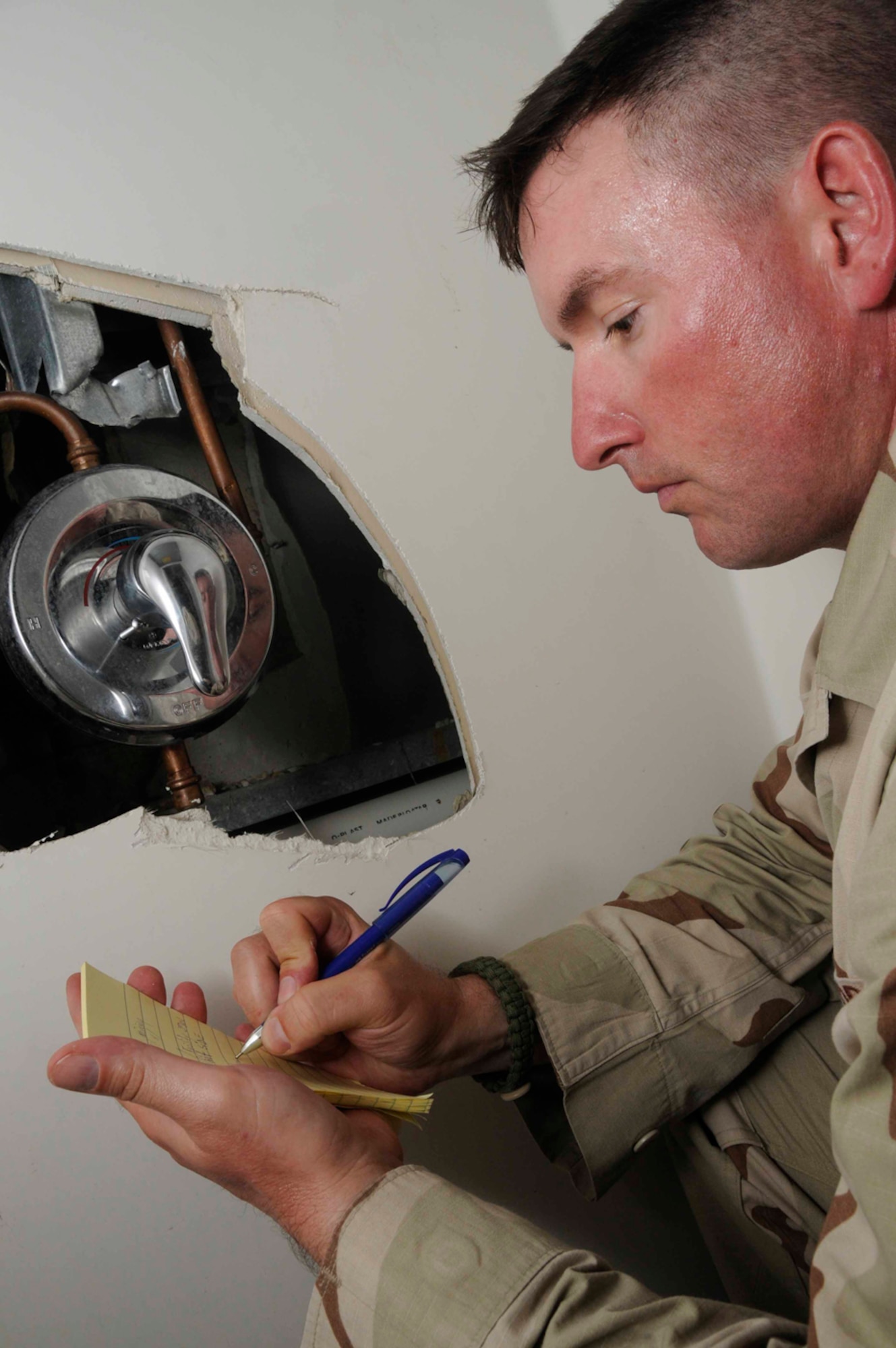Staff Sgt. James Thomas, 379th Expeditionary Civil Engineer Squadron, writes the specifications of a shower mixing valve for a sheet metal replacement in a cadillac July 30 in Southwest Asia. Cadillacs are bathroom facilities for deployed military members and its Sergeant Thomas’ job to perform daily maintenance on it. Sergeant Thomas is a utility craftsman deployed from Charleston Air Force Base, S.C. (U.S. Photo/Staff Sgt. Darnell T. Cannady)
