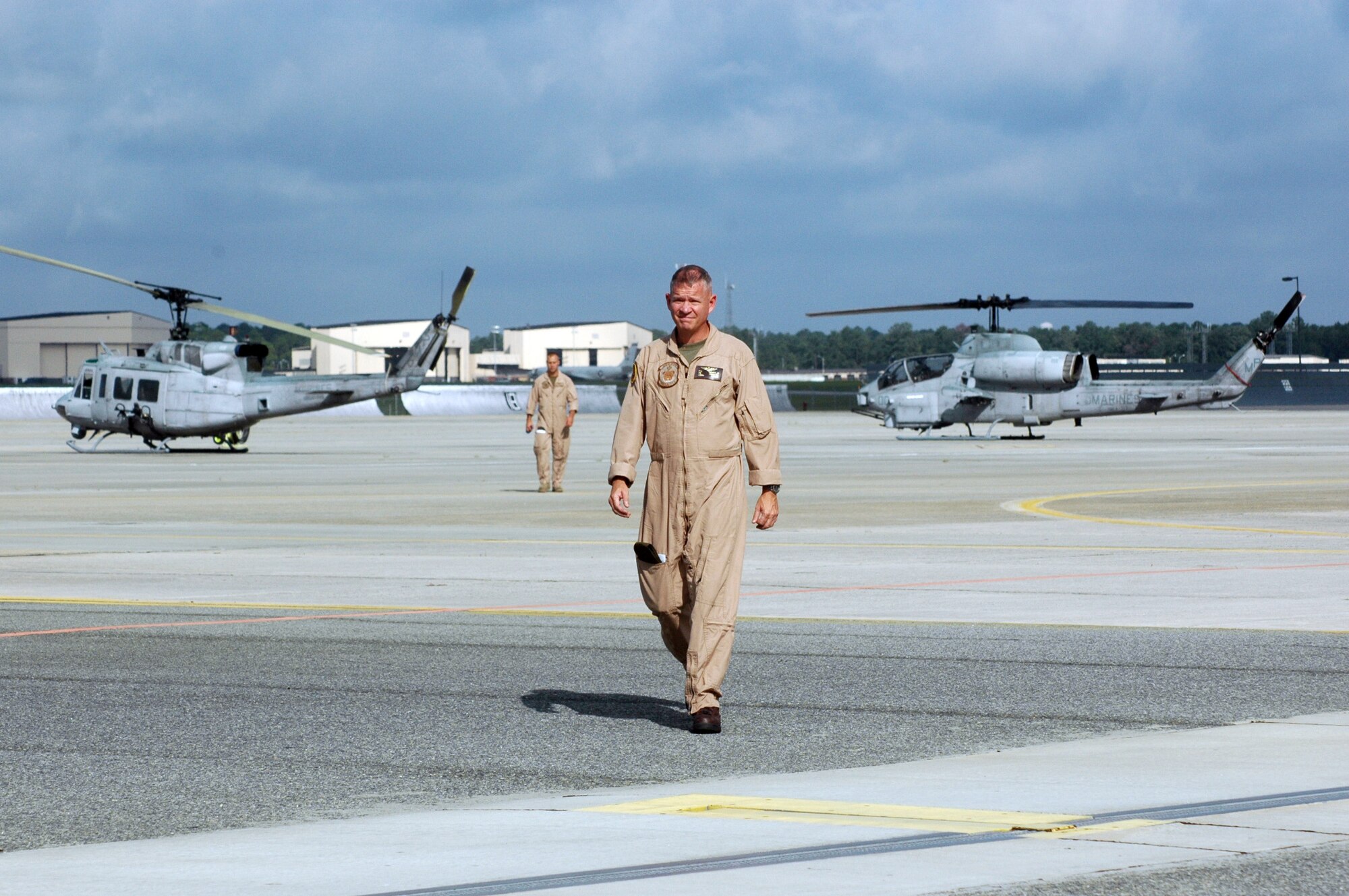 Lt. Col. Paul Ozmer, Jr., HMLA-733 commanding officer, walks across the flightline where a UH-1 Huey and an AH-1 Cobra was parked during the groundbreaking ceremony for the new Marine Light/Attack Helicopter Squadron 773 hanger. U. S. Air Force photo by Sue Sapp