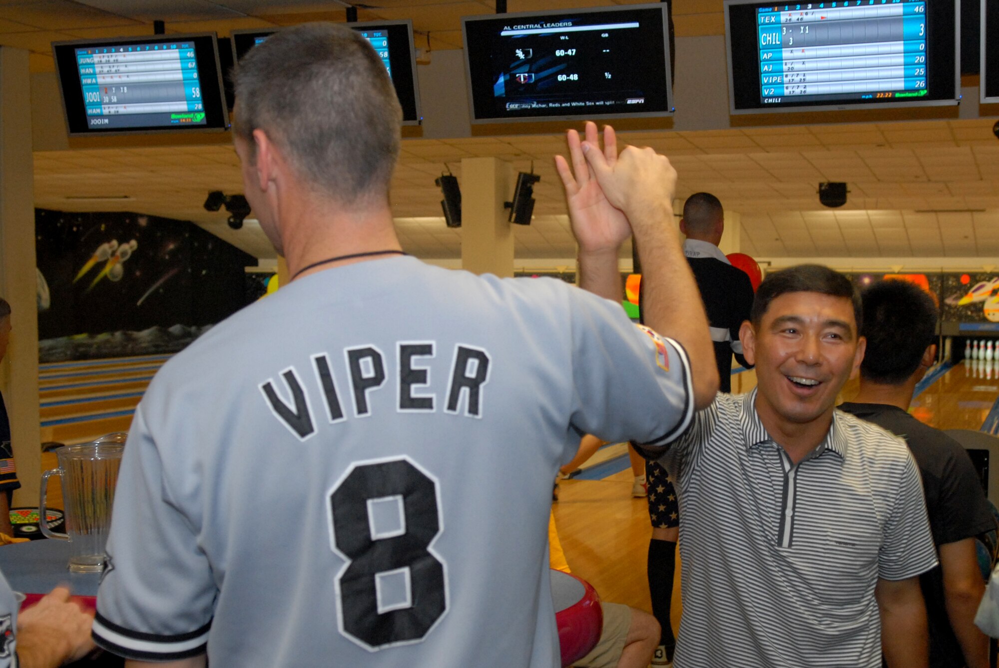 KUNSAN AIR BASE, Republic of Korea -- Colonel Peter Gersten, 8th Operations Group commander, gives a high five to Republic of Korea Col. Sung Ryong Ha, 38th Fighter Group commander, during the friendly bowling completion here August 1. The 8th Force Support Squadron gave out first, second and third place prizes for the best teams--there were six Wolf Pack teams and six ROCAF teams total.(US Air Force Photo By: Angela Ruiz)