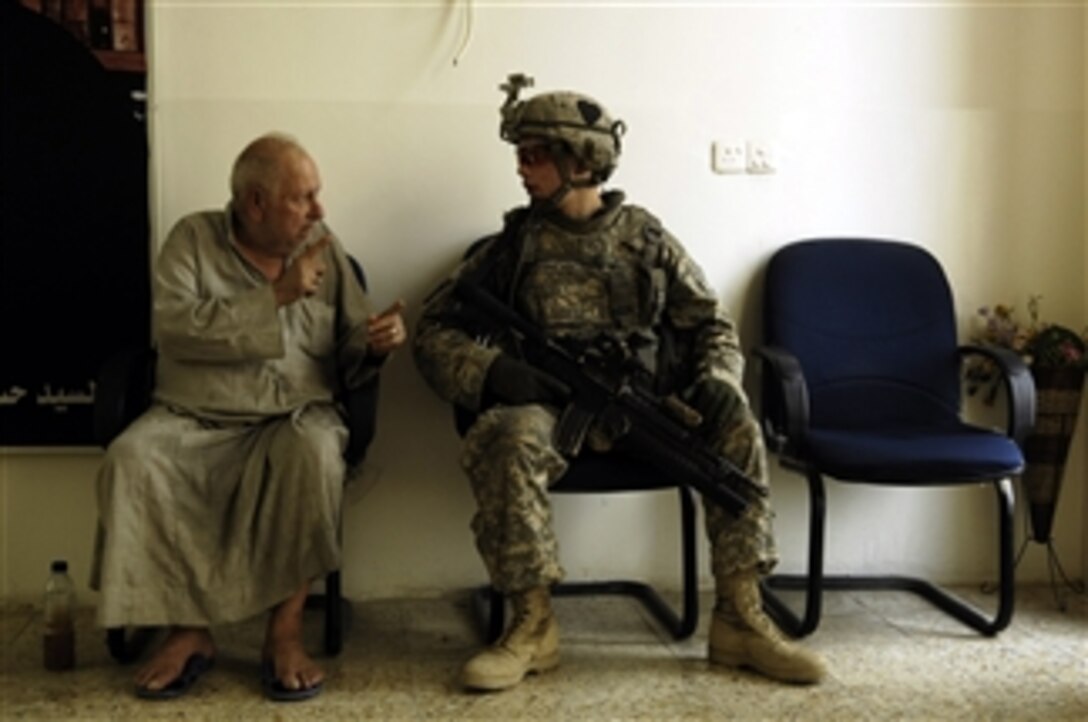U.S. Army Pfc. Skyler Rosenberry speaks with an Iraqi man while visiting a home for the elderly in Kadhimiya, Iraq, on July 30, 2008.  Rosenberry is assigned to 4th Platoon, Delta Company, 1st Battalion, 502nd Infantry Regiment, 2nd Brigade Combat Team, 101st Airborne Division.  