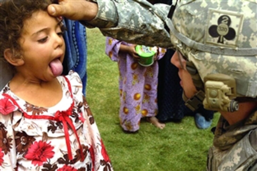 U.S. Army Capt. Damien Barrineau examines an Iraqi girl’s throat while providing medical care to the people of Sayid Ghrib, Iraq, July 27, 2008. Barrineau is assigned to the 101st Airborne Division's 2nd Battalion, 320th Field Artillery Regiment. 