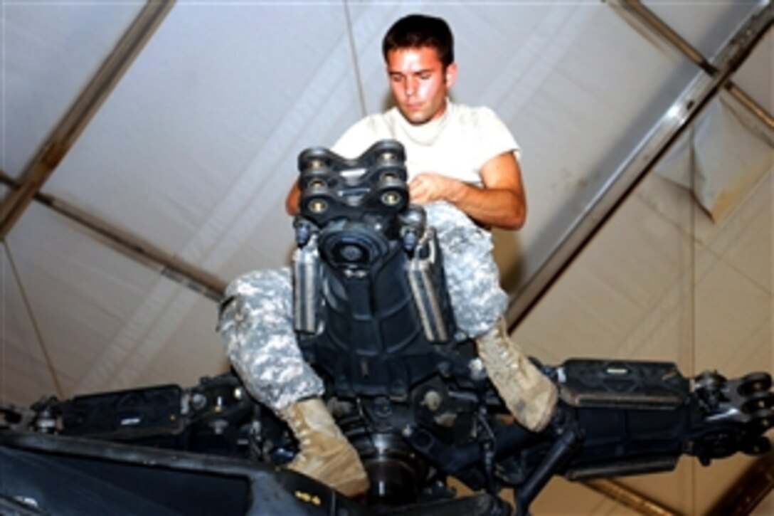U.S. Army Cpl. Christopher Spencer works on an Apache helicopter on the flight line of Camp Taji, Iraq, July 29, 2008. Spencer is a Apache helicopter mechanic assigned to the 4th Infantry Division's 4th Battalion, 4th Aviation Regiment, Combat Aviation Brigade.