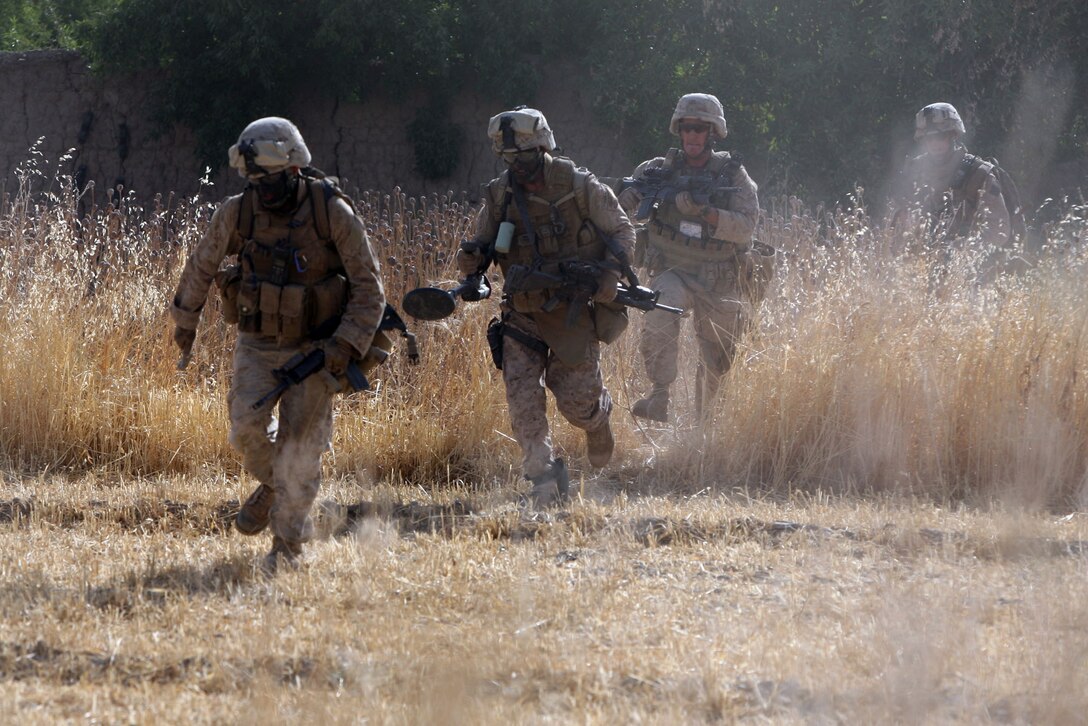 Combat engineers of Task Force 2nd Battalion, 7th Marine Regiment, 1st Marine Division, run back to a safe position after placing a wall charge to breach a Taliban headquarters. ::r::::n::::r::::n::