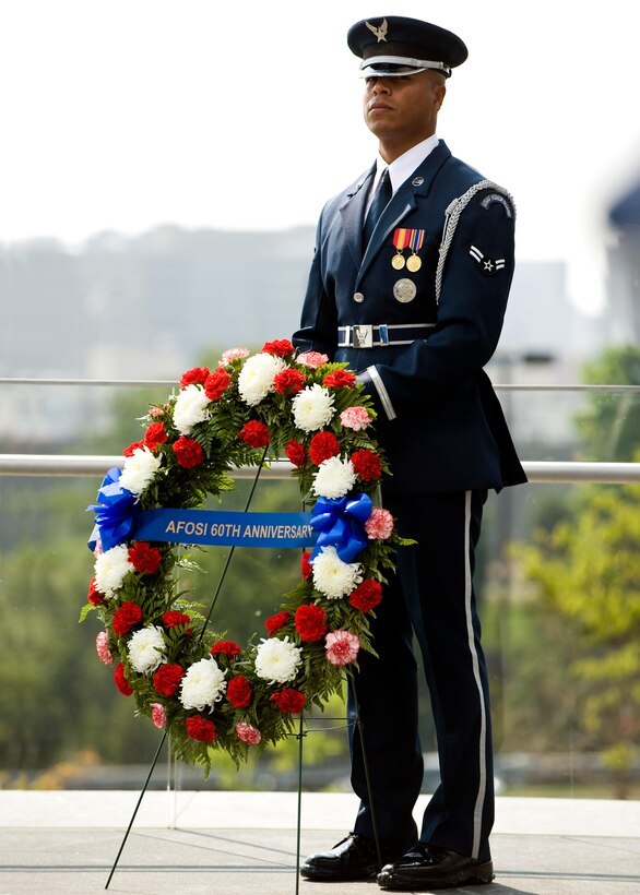 An Airman from the Air Force Honor Guard stands solemn duty behind a wreath placed at the Air Force Memorial in observance of the 60th Anniversary of the Air Force Office of Special Investigations. (U.S. Air Force photo/Mike Hastings)