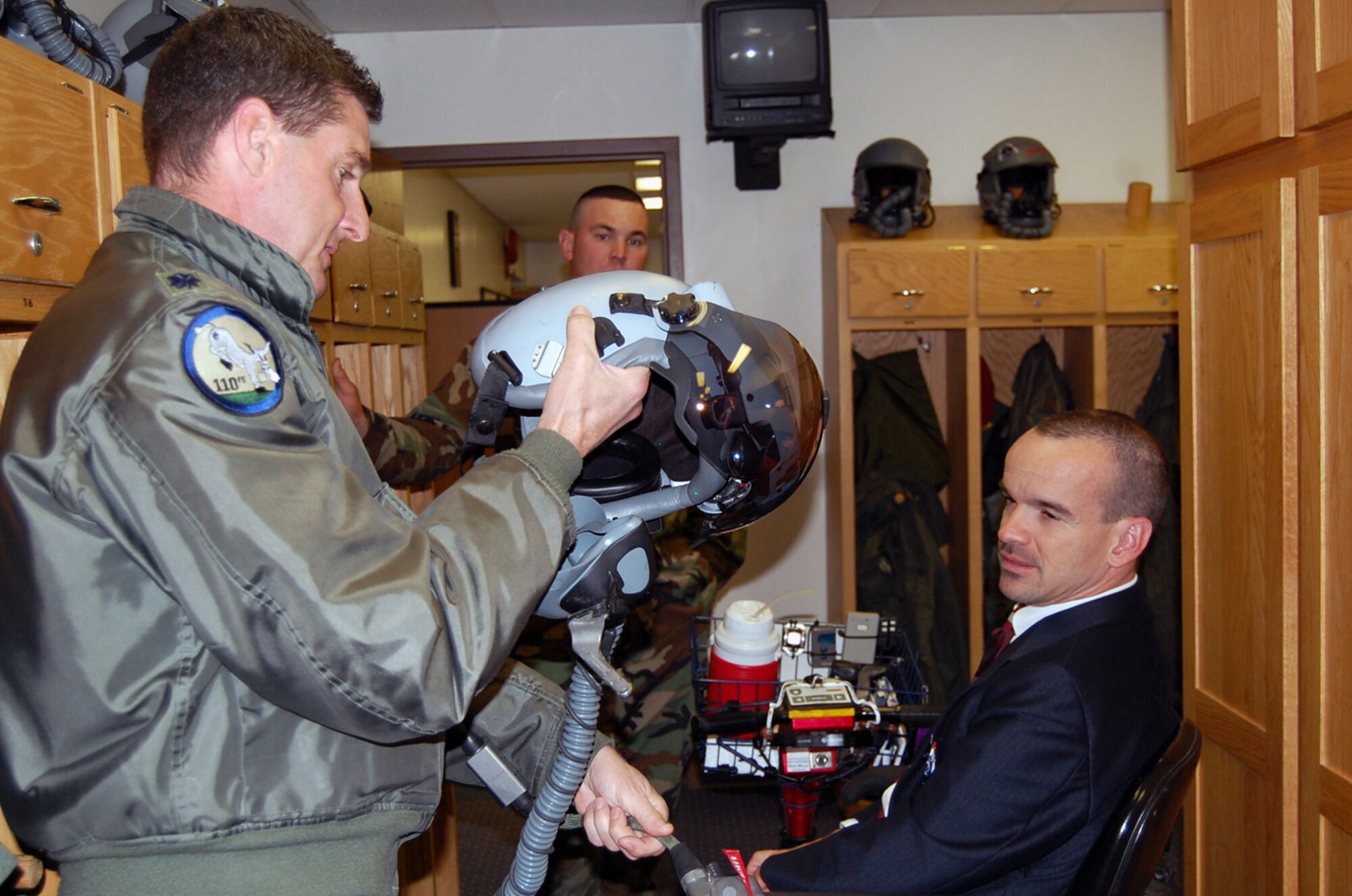 Lt. Col. Mike Flanagan, 131st Operations Group, explains the helmet that the pilots wear in flight to Willie "Wild Man" Deuster.  Deuster was the speaker for the Brown Bag Speaker Series May 3.