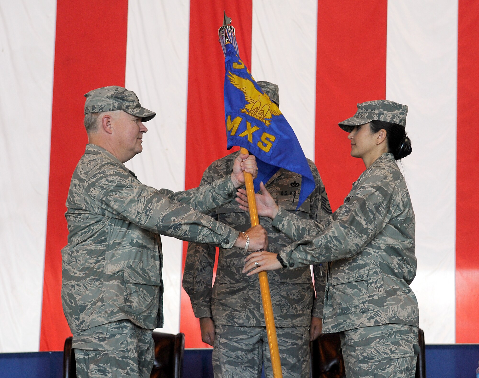 Left, Col. Jim Weber, 305th Maintenance Group commander, hands over the 305th Maintenance Squadron guidon to Maj. Elizabeth Clay, incoming 305th MXS commander, at a change of command ceremony Aug. 1 here. Lt. Col. David Pastore relinquished command of the 305th MXS to become the 605th Aircraft Maintenance Squadron commander Aug. 1. (U.S. Air Force photo/Kenn Mann)