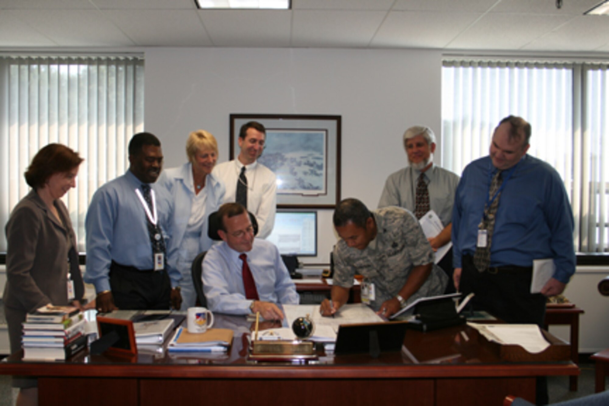 HANSCOM AFB, Mass. - Frank Weber (seated), director of the 554 Electronic Systems Wing, and other wing members look on as wing vice director Col. Derrick Richardson signs the Voluntary Protection Program Safety Pledge. (Courtesy photo)