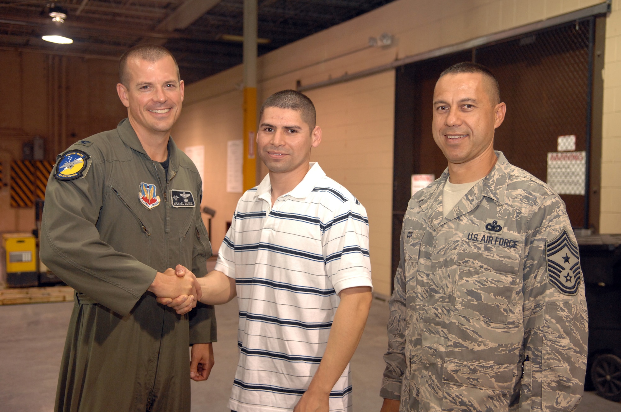 Staff Sgt. Bernaby Rodriguez, 49th Logistic Readiness Squadron, shakes hands with Col. Michael Magee, 49th Fighter Wing vice commander, and poses for a photo along with Command Chief Master Sgt. Jeffrey Cui, 49th Fighter Wing command chief. Colonel Magee and Chief Cui were a few of the many people who waited at the armory at Holloman Air Force Base, N.M., July 25, for Sergeant Rodriguez who was returning from a six-month deployment to Balad Air Base, Iraq. (U.S. Air Force photo/Airman Sondra M. Wieseler)