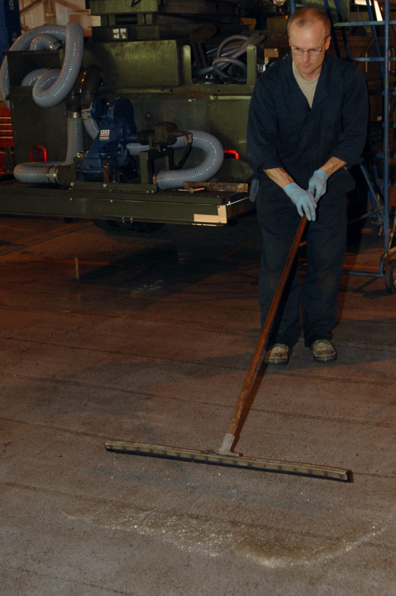 Tech. Sgt. Carl Vickes, 446th Logistic Readiness Flight, McChord Air Force Base, Wash., cleans excess water from the maintenance floor after conducting a leak test on a vehicle here July 25, 2008. (U.S. Air Force photo by Senior Airman Teresa M. Hawkins)