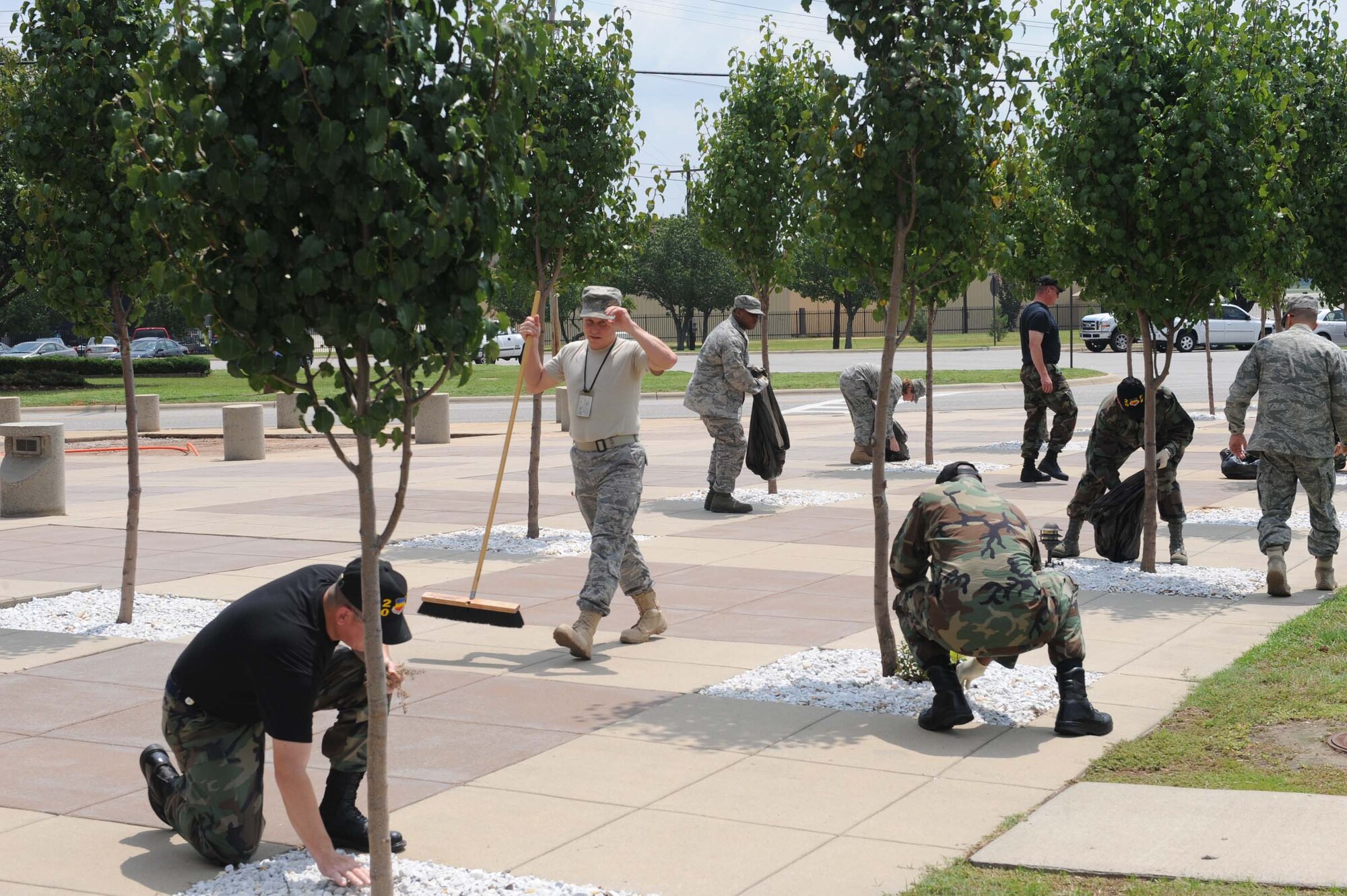 SHAW AIR FORCE BASE, S.C. -- Airmen from the 20th Fighter Wing staff pick and sweep up debris around the trees adjacent to Wing HQ during base clean up day Aug 1. Agencies across base were given the opportunity to clean their work space in and out prior to the LSET inspection. (U.S. Air Force photo/Staff Sgt. Henry Hoegen)