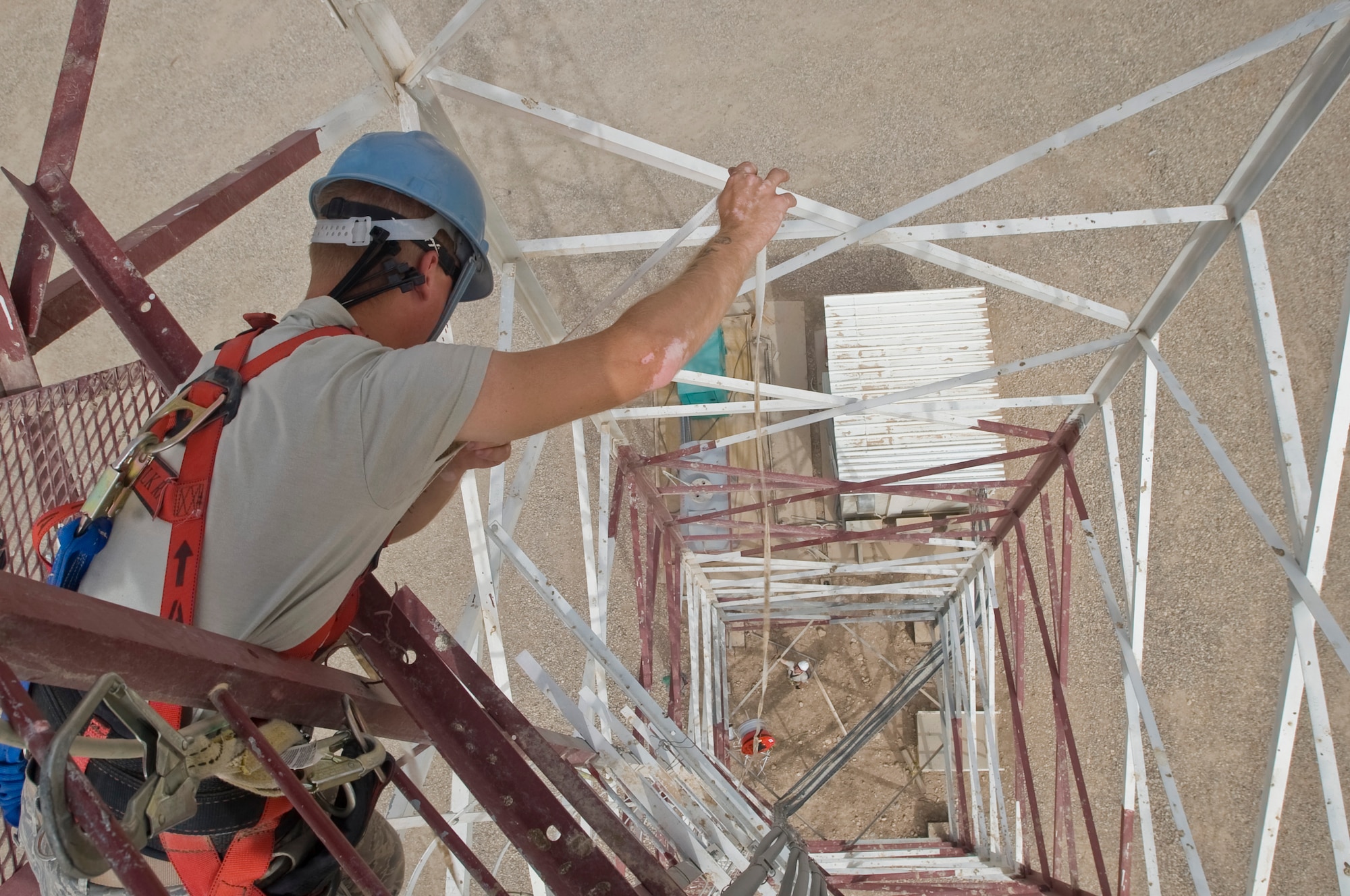 ALI BASE, Iraq --Senior Airman George Carameta, 407th Expeditionary Communications Squadron network technician, lowers an aircraft obstruction light down to Staff Sgt. Ray Stetler, 407th ECS base information and infrastructure NCOIC, Aug. 2, 2008. The aircraft obstruction lighting keeps multi-million dollar aircraft from colliding into the towers when visibility is low, either due to darkness or weather conditions. Both Airman Carameta and Sergeant Stetler are deployed from Tinker Air Force Base, Okla. (U.S. Air Force photo/Airman 1st Class Christopher Griffin)