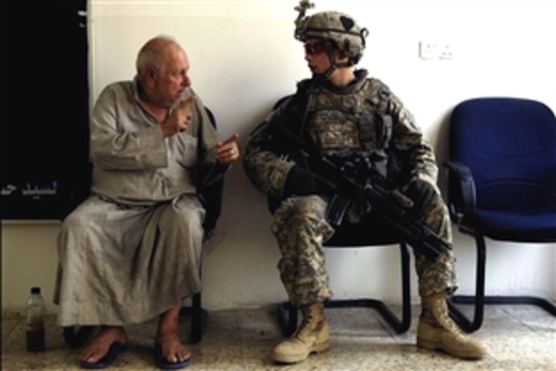 U.S. Army Pfc. Skyler Rosenberry talks with an Iraqi man in a waiting room of a home for the elderly in Kadhimiya, Iraq, July 30, 2008. Rosenberry and other U.S. soldiers assigned to the 101st Airborne Division's 1st Battalion, 502nd Infantry Regiment, visited the nursing home. 

