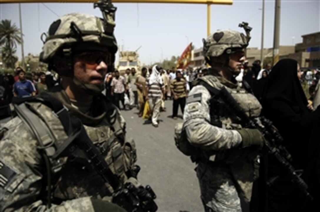 U.S. Army Pfc. Skyler Roseenberry and Sgt. Michael Bearden walk on a street crowded with pilgrims during the Shiite Muslim ceremony commemorating the death of Mousa Al-Kadhim, the 7th Imam, in Kazimiyah, Iraq, on July 29, 2008.  Each year devout Shiites gather at a mosque believed to sit on top of the grave site of the Imam.  