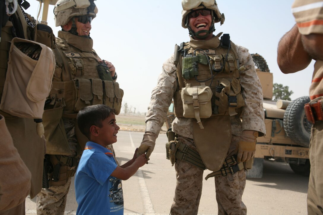Maj. Eric P. Dominijanni, team leader, Police Transition Team 8, Regimental Combat Team 1, laughs with 5-year-old Ahmed and his father before the two Iraqis climbed aboard an aircraft headed to Ahman, Jordan.