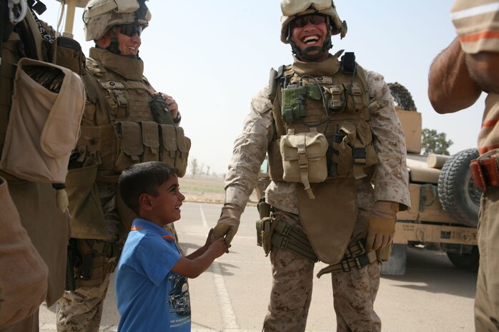 Maj. Eric P. Dominijanni, team leader, Police Transition Team 8, Regimental Combat Team 1, laughs with 5-year-old Ahmed and his father before the two Iraqis climbed aboard an aircraft headed to Ahman, Jordan.