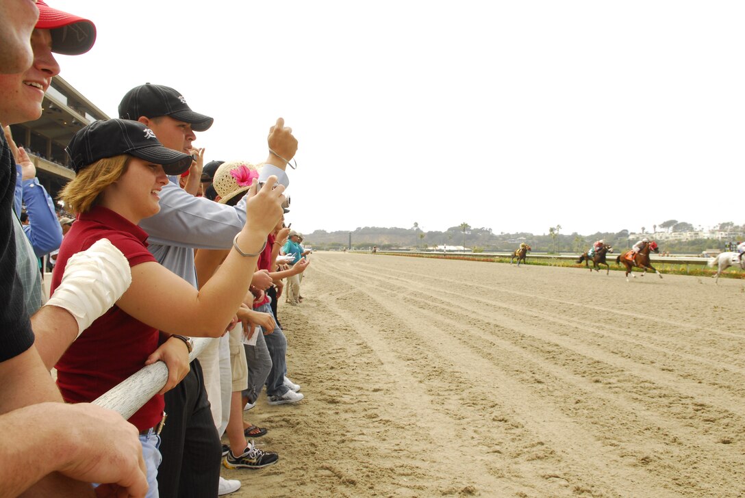 Marines from Marine Medical Rehabilitation Platoon and their families, Headquarters and Service Battalion here, Wounded Warrior Battalion West at Camp Pendleton, Calif., and Marine Light Attack Training Squadron-303, Camp Pendleton, cheer for their favorite horses as they speed past during a race at the Del Mar Track Aug. 4.