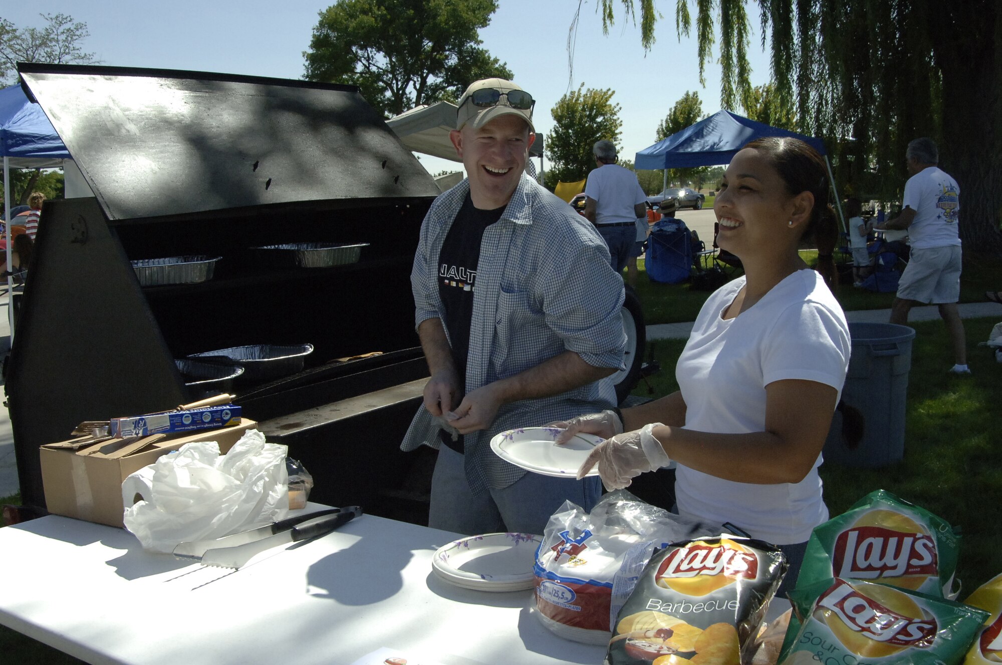 MOUNTAIN HOME AIR FORCE BASE, Idaho --Tech. Sgts Jeff Scarlott (left) and Michelle Iglesias, help cook and serve food at the Focus 56 Auto Showdown, which took place Aug. 2 at Holt Park. Forty cars, seven trucks and four motorcycles were registered for the auto show, which raised more than $900 for the Focus 56 council. The event was made possible by the hard work of more than 50 volunteers from across the wing. (U.S. Air Force photo by Staff Sgt. Jasmine Reif) 