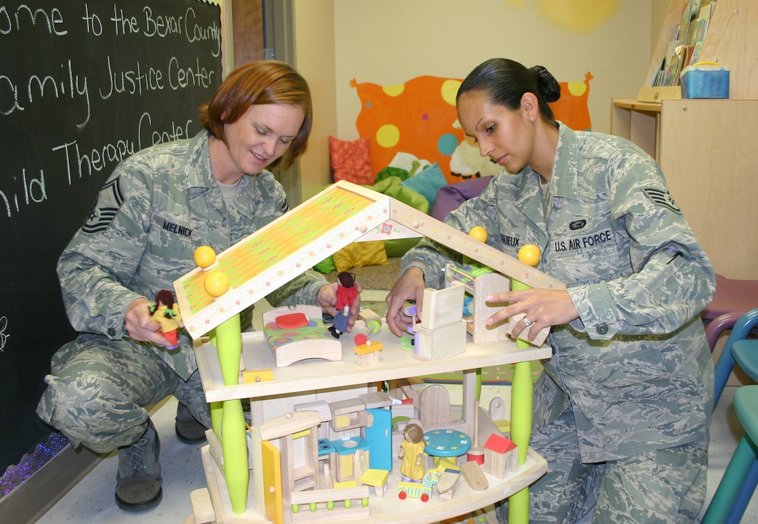 Senior Master Sgt. Carianne Melnick and Staff Sgt. Aidaliz Lagueux, both of the Air Force Personnel Center here, put the final touches on a dollhouse that will help children at a new child therapy center located in downtown San Antonio. (U.S. Air Force photo/Richard Salomon) 