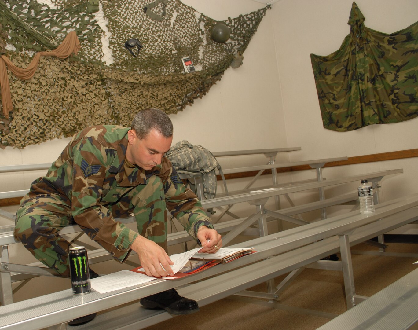 Staff Sgt. Ryan Kennedy, 12th Security Forces Squadron, fills out paperwork during the last deployment line at the former deployment readiness center in Hangar 52 July 23. The DRC moved to Hangar 71 in an effort to streamline information distribution and equipment storage for servicemembers and civilians training for and deploying to support the Global War on Terror. (U.S. Air Force photo by Steve White)
