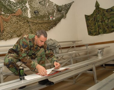 Staff Sgt. Ryan Kennedy, 12th Security Forces Squadron, fills out paperwork during the last deployment line at the former deployment readiness center in Hangar 52 July 23. The DRC moved to Hangar 71 in an effort to streamline information distribution and equipment storage for servicemembers and civilians training for and deploying to support the Global War on Terror. (U.S. Air Force photo by Steve White)