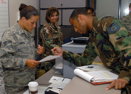 Senior Airman Andrea Murcia, 12th Comprtoller Squadron, speaks with Tech. Sgt. Desmond Savage, 12th Operations Support Squadron, about his financial paperwork during the last deployment line at the former deployment readiness center in Hangar 52 July 23. The DRC moved to Hangar 71 in an effort to streamline information distribution and equipment storage for servicemembers and civilians training for and deploying to support the Global War on Terror. (U.S. Air Force photo by Steve White)