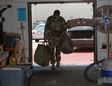 All geared up, Staff Sgt. Cory Chandler, 12th Contracting Squadron, leaves the new deployment readiness center July 25. The DRC moved to Hangar 71 in an effort to streamline information distribution and equipment storage for servicemembers and civilians training for and deploying to support the Global War on Terror. Sergeant Chandler is the first person to deploy from the DRC's new location. (U.S. Air Force photo by Rich McFadden)