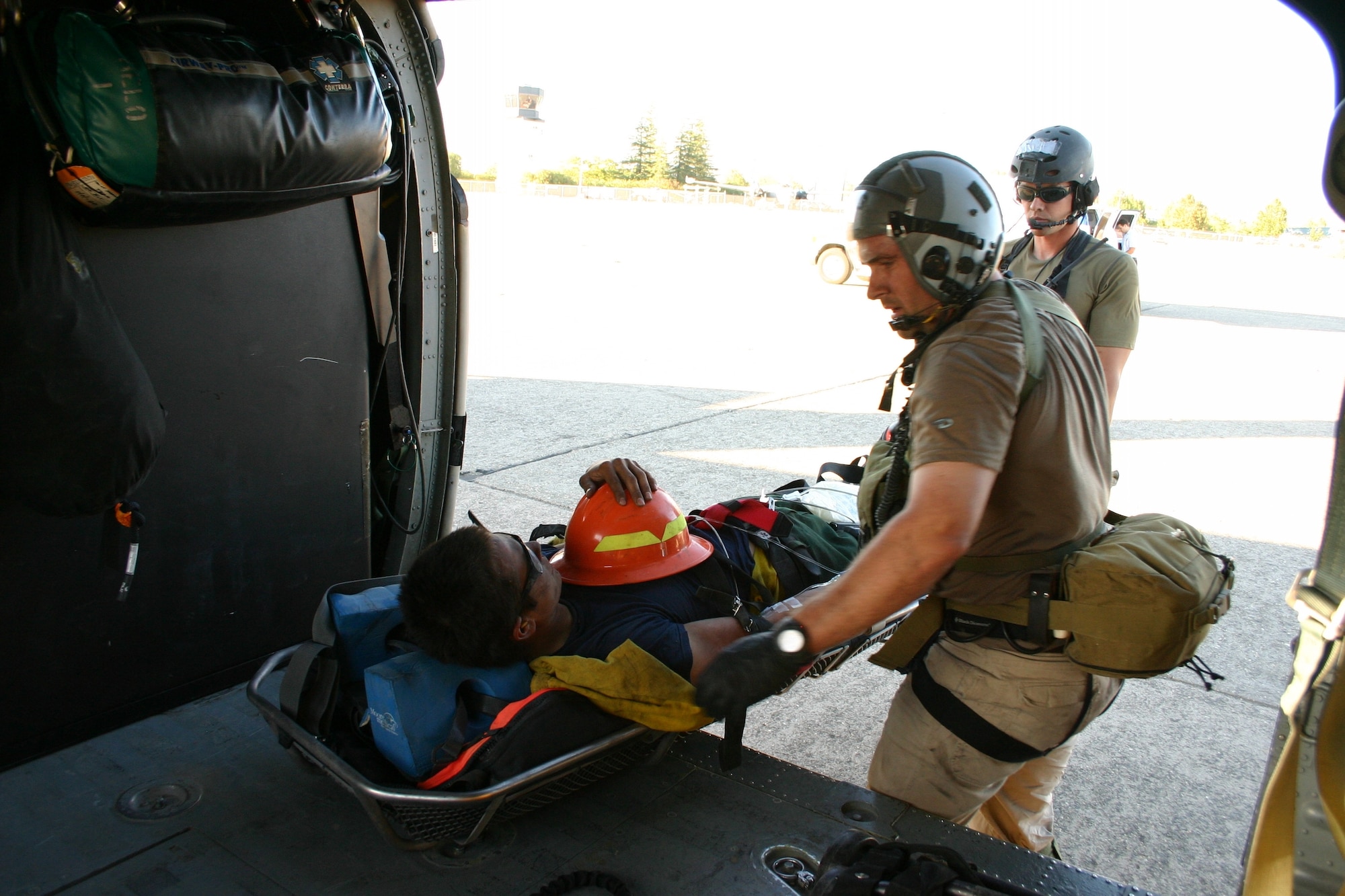 Tech. Sgt. Michael Bendle (left) and Staff Sgt. Seth Zweben (right), pararescuemen from the 131st Rescue Squadron, prepare to transfer a firefighter off of the 129th Rescue Wing-based HH-60G Pave Hawk to an awaiting ambulance at the Chico Municiple Airport, Calif., Aug. 4. The firefighter was working in the Feather River Complex near French Bear, Calif., when he suffered a heat stroke. The 129th Rescue Wing aircrew and pararescuemen hovered over steep terrain and hoisted the firefighter up in to the Pave Hawk. The total number of people saved by the 129th RQW is 561. (U.S. Air Force photo by Tech. Sgt. Brock Woodward) 