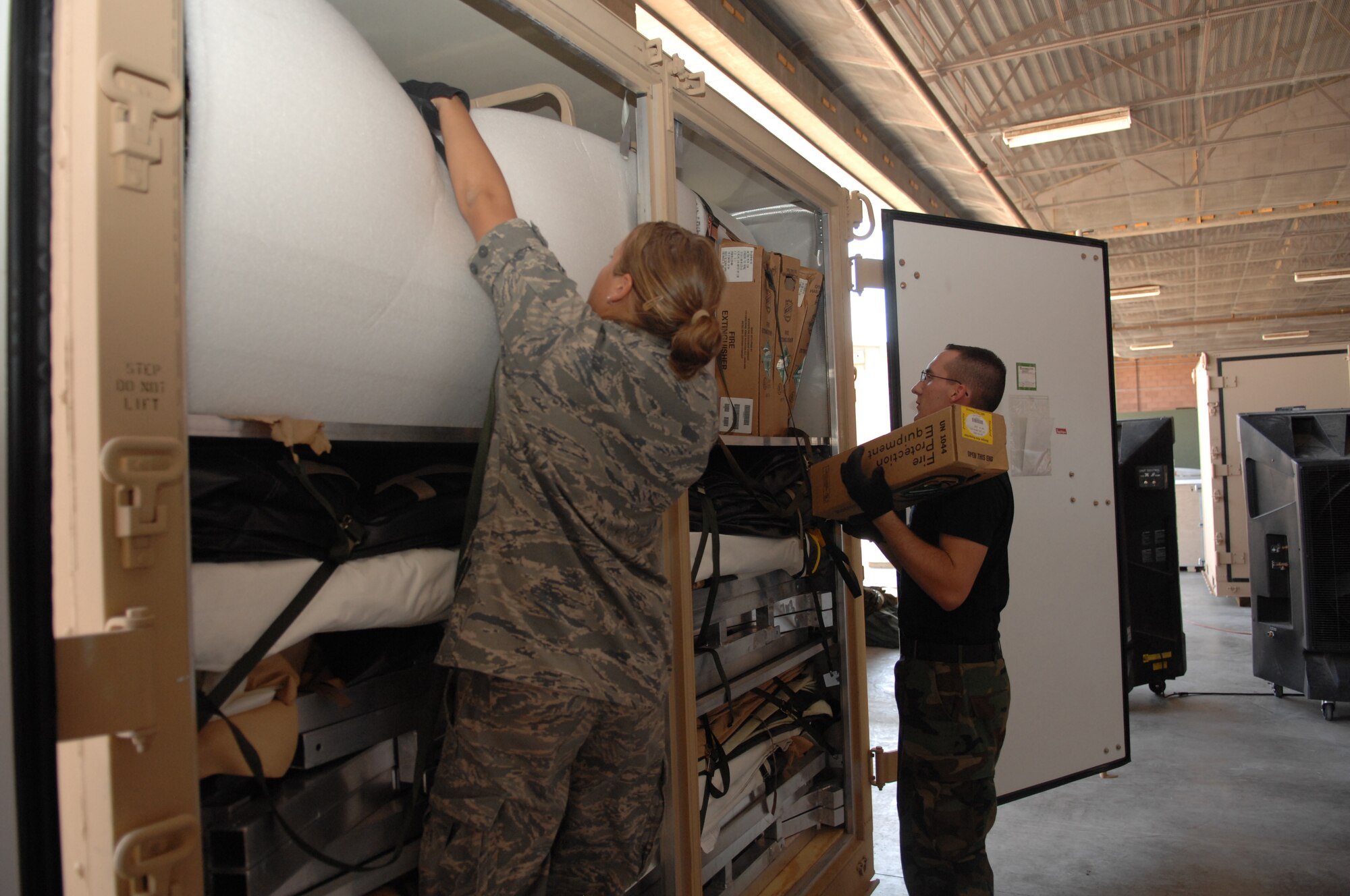 Airman 1st Class Alan Stewart and Airman 1st Class Brittany Brunkhorst, both of the 49th Materiel Maintenance Support Squadron, removes the items from a Unit Type Code at Basic Expeditionary Airfield Resources (BEAR) Base at Holloman Air Force Base, N.M., August 1. The Airmen are revamping it from the original BEAR UTC to a BEAR Order of Battle UTC, better known as BOB. This involves removing the items and repacking them into a different configuration. (U.S. Air Force photo/Airman Sondra M. Wieseler)