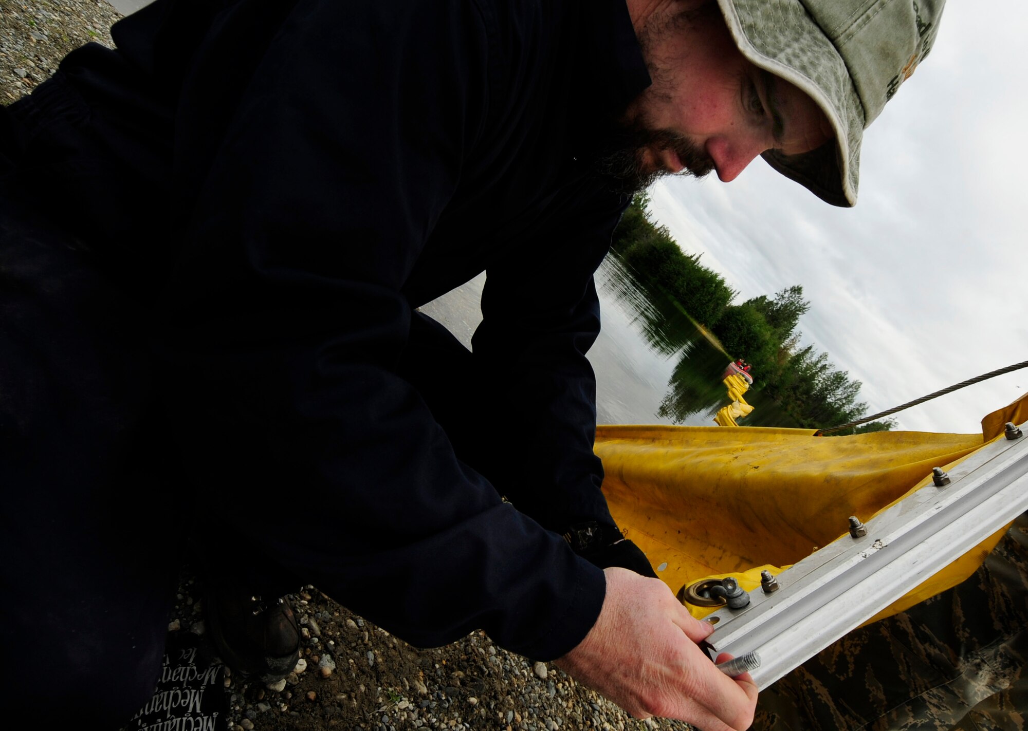 Mr.Scott Caple, a U.S Navy Supervisor of Salvage Mechanic Operator inspects the connection of a contamination boom to ensure connection points are in their proper place prior to an oil and light fuels spill water contamination clean-up exercise July 23, 2008 at Eielson Air Force Base, Alaska. This exercise is an annual requirement based on the Oil Pollution Act of 1990. (U.S Air Force Photo by Tech Sgt Eric T. Sheler)