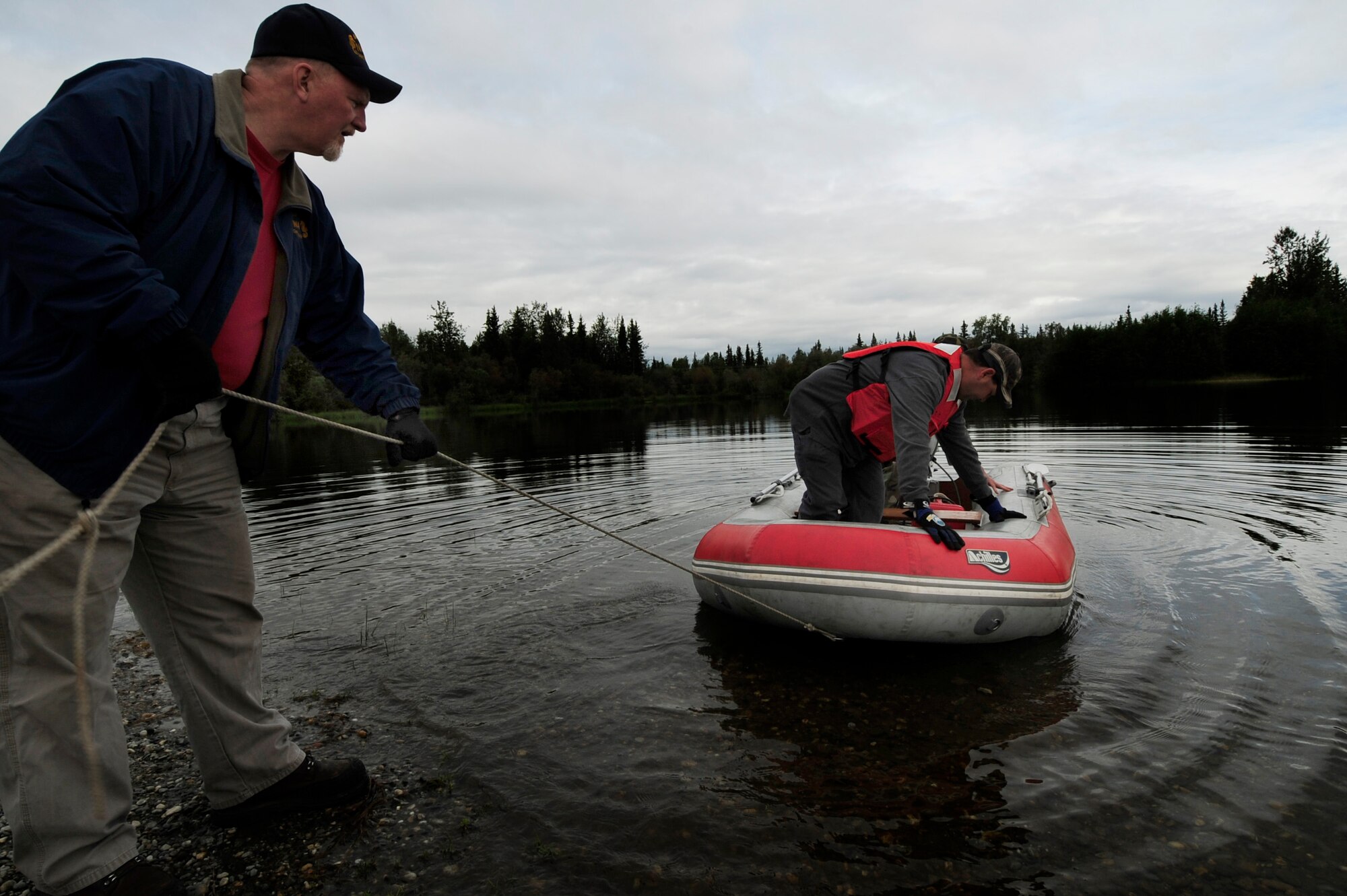 Mr. Dale Colby, a U.S Navy Supervisor of Salvage contractor launches a inflatable raft with 354th Civil Engineer Liquid Fuels shop personnel Senior Airman Justin Vickery and Mr. Brent Perry  in preparation for a oil and light fuels spill water contamination clean-up exercise July 23, 2008 at Eielson Air Force Base, Alaska . SrA Vickery and Mr. Perry will take the raft to the opposite side of Bear Lake to help set up a contamination boom. This exercise is an annual requirement based on the Oil Pollution Act of 1990. (U.S Air Force Photo by Tech. Sgt. Eric T. Sheler)