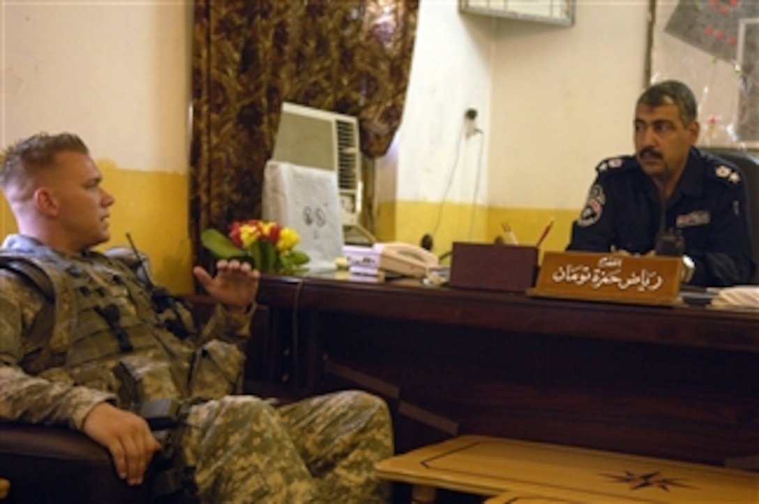 U.S. Army Sgt. Daniel Mulford, team leader of 16th Military Police Brigade, 511th Military Police Company, 1st Platoon, 2nd Squad, meets with Iraqi Police Chief of the Hussein Station Lt. Col. Raxaq during a routine visit to the station in Diwaniyah, Iraq, to discuss the stationís improvements on July 30, 2008.  