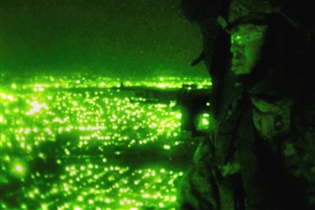 Seen through a night viewing device, U.S. Army Master Sgt. Towanga Dyson flies over Baghdad, Iraq, in a Black Hawk helicopter during a leaflet mission, Aug, 3, 2008. Dyson is assigned to the 4th Infantry Division's 312th Psychological Operation Company. 

