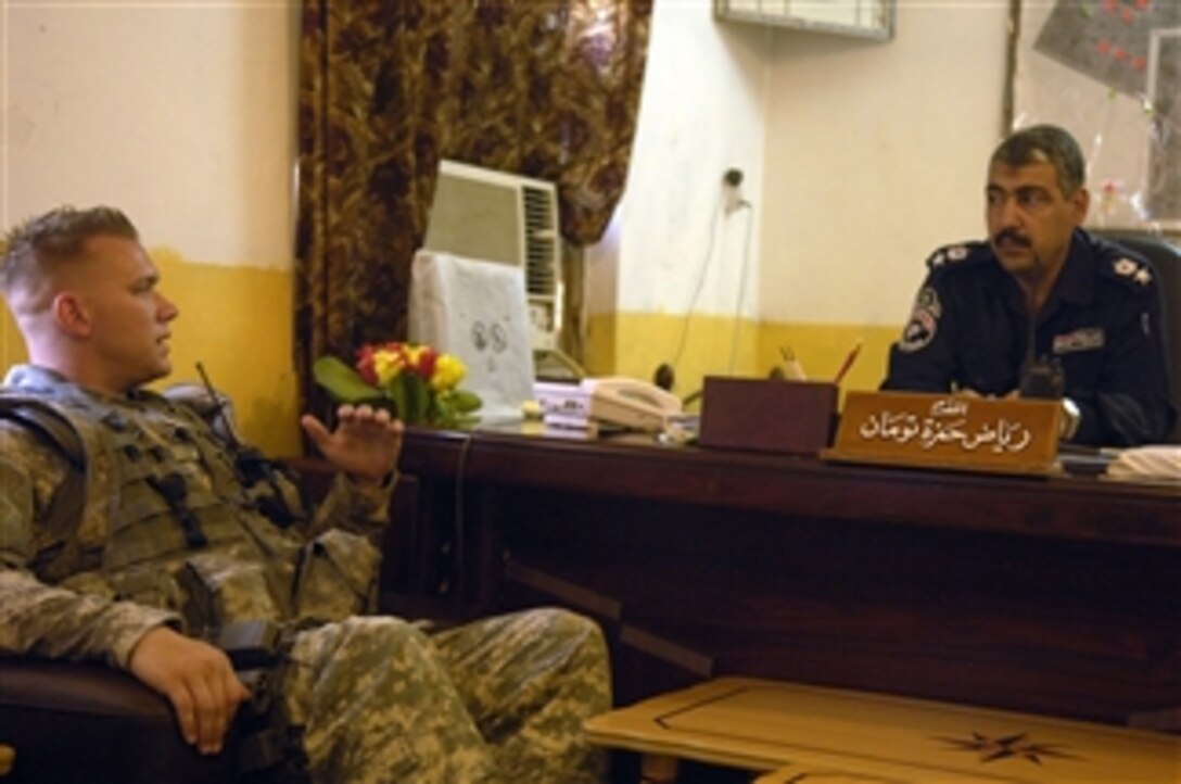 U.S. Army Sgt. Daniel Mulford, team leader of 16th Military Police Brigade, 511th Military Police Company, 1st Platoon, 2nd Squad, meets with Iraqi Police Chief of the Hussein Station Lt. Col. Raxaq during a routine visit to the station in Diwaniyah, Iraq, to discuss the stationís improvements on July 30, 2008.  