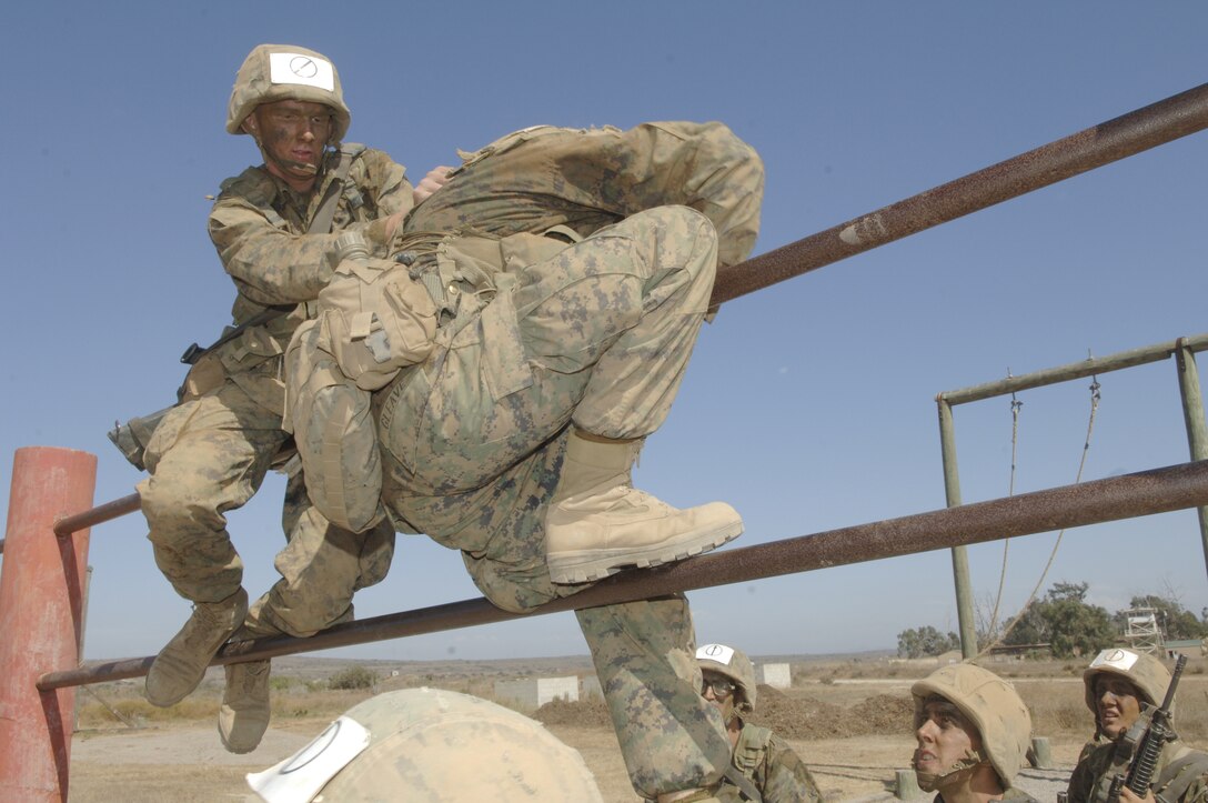 Recruit Aaron W. Greene, Platoon 3209, helps a teammate over a double high bar obstacle.  From the moment recruits begin their training at boot camp, they are taught that teamwork is very important to mission accomplishment.