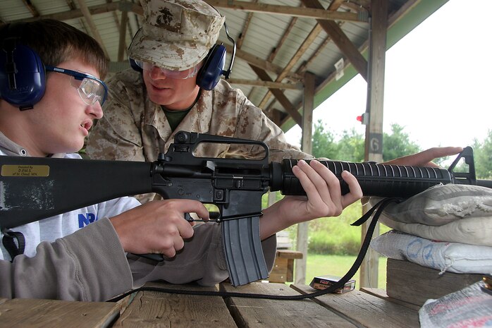 Private Cory Spires, a Marine on recruiter assistance with Recruiting Substation Janesville, explains sight alignment and sight picture to poolee William Olson, a poolee out of Milton, Wis.,  Poolees from Marine Corps Recruiting Station Milwaukee fire the AR-15 rifle during a familiarization rifle range August 4-7 at the Stone Bank Sportsman's Club in Oconomowoc, Wis.  This pool function allowed poolees to learn about the AR-15, the civilian version of the M-16 A2 service rifle, to include weapons safety, weapons handling, trigger control, breath control and to become familiar with a weapon similar to what they will be firing in boot camp.