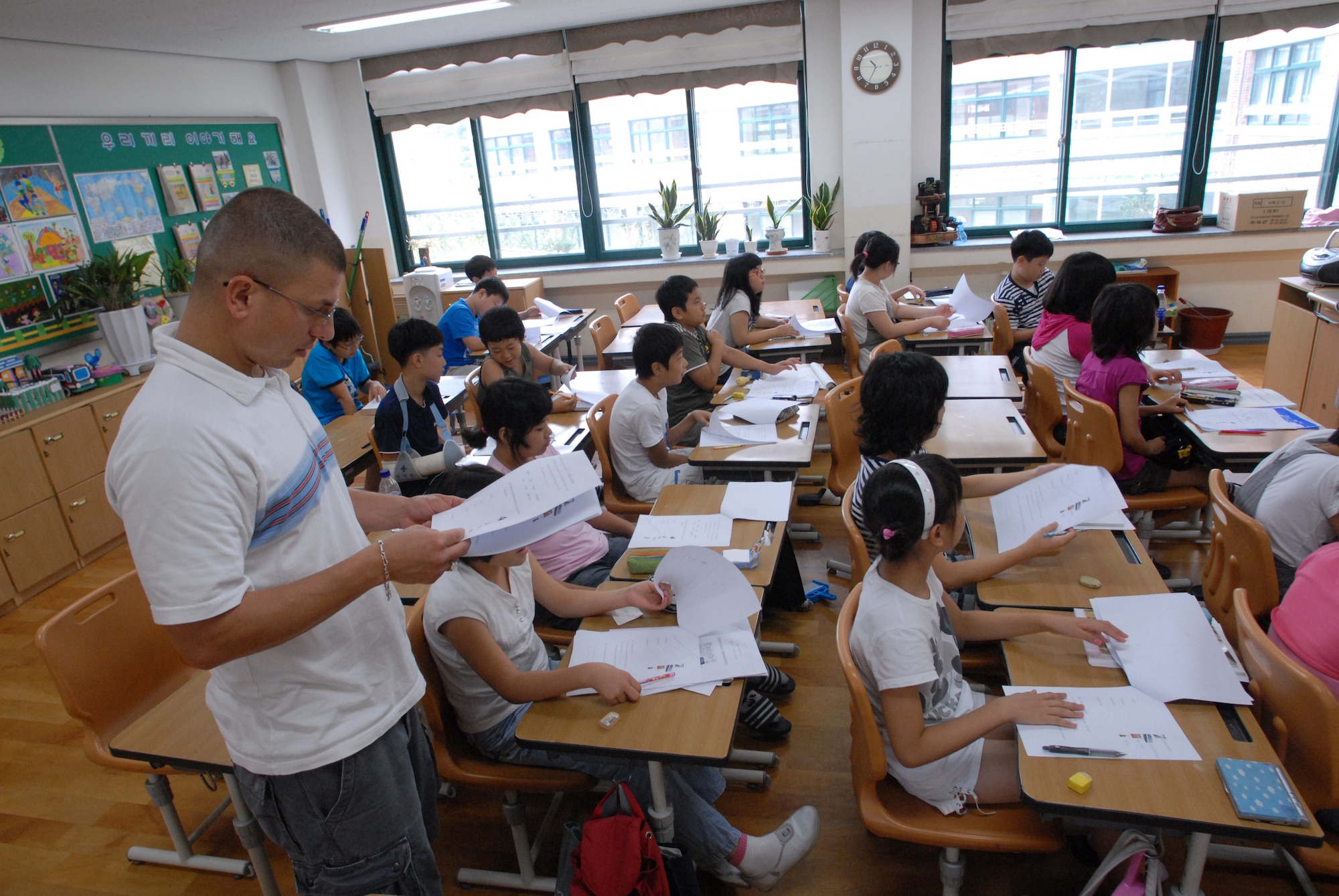 KUNSAN AIR BASE, Republic of Korea— Technical Sergeant Scott Ibanez, 8th Maintenance Squadron, reads the study worksheets for the Kunsan-Sponsored English Camp at the Jinp'yo Elementary School, Gunsan City July 30. 15 Airmen Volunteered to help teach More Than 60 elementary and middle grade Korean students that participated in the English Camp.(US Air Force Photo By: Senior Airmen Angela Ruiz)