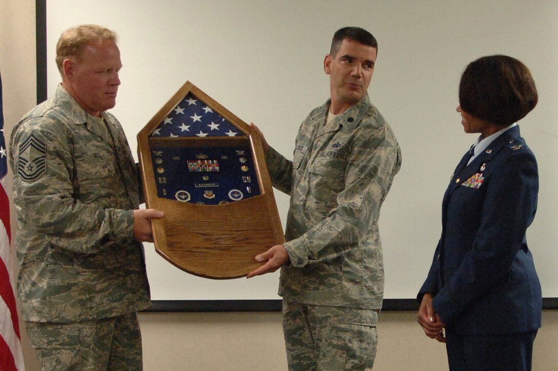 ELLSWORTH AIR FORCE BASE, S.D. - Col. Renita Alexander (right), former 28th Mission Support Group commander, receives a shadow box from Lt. Col. Dean Hullings (center), 28th Mission Support Group deputy commander,  and Chief Master Sgt. Rick Ives (left), 28th Mission Support Group chief enlisted manager, reflecting her 26 years of service to the U.S. Air Force. Colonel Alexander started her career as the officer-in-charge of material control at the 31st Fighter Wing, Homestead AFB, Fla., and ended as the 28th Mission Support Group commander here. (U.S. Air Force photo/Senior Airman Kasey Zickmund)