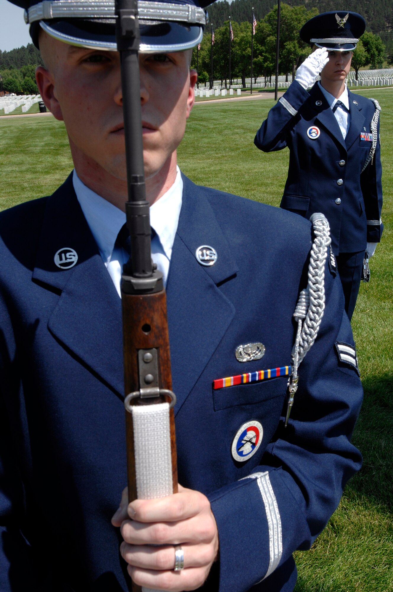 (Left) Airman 1st Class Ray Wahl and Staff Sgt. Patricia Lock, Ellsworth Air Force Base Honor Guard members, render a salute during the playing of taps at the Black Hills National Cemetery, July 31. The honor guard paid their respects during a funeral service held for a retired Air Force master sergeant. (U.S. Air Force photo/Senior Airman Marc I. Lane)(Released)