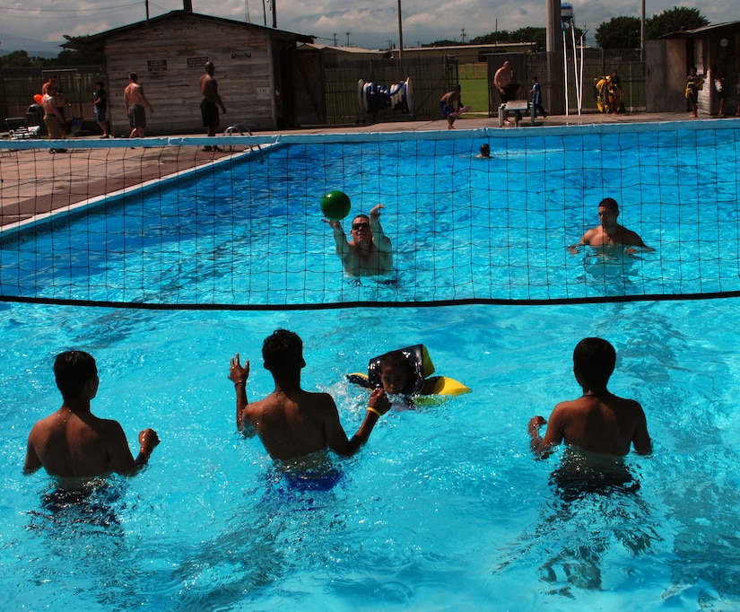 Servicemembers from Soto Cano Air Base play volleyball in the base pool with boys from the Hogar de Ninos Nazareth Orphanage in Comayagua, Honduras. Nearly 60 Soldiers, Sailors and Airmen volunteered for the orphanage kids' day Aug. 2 on base.