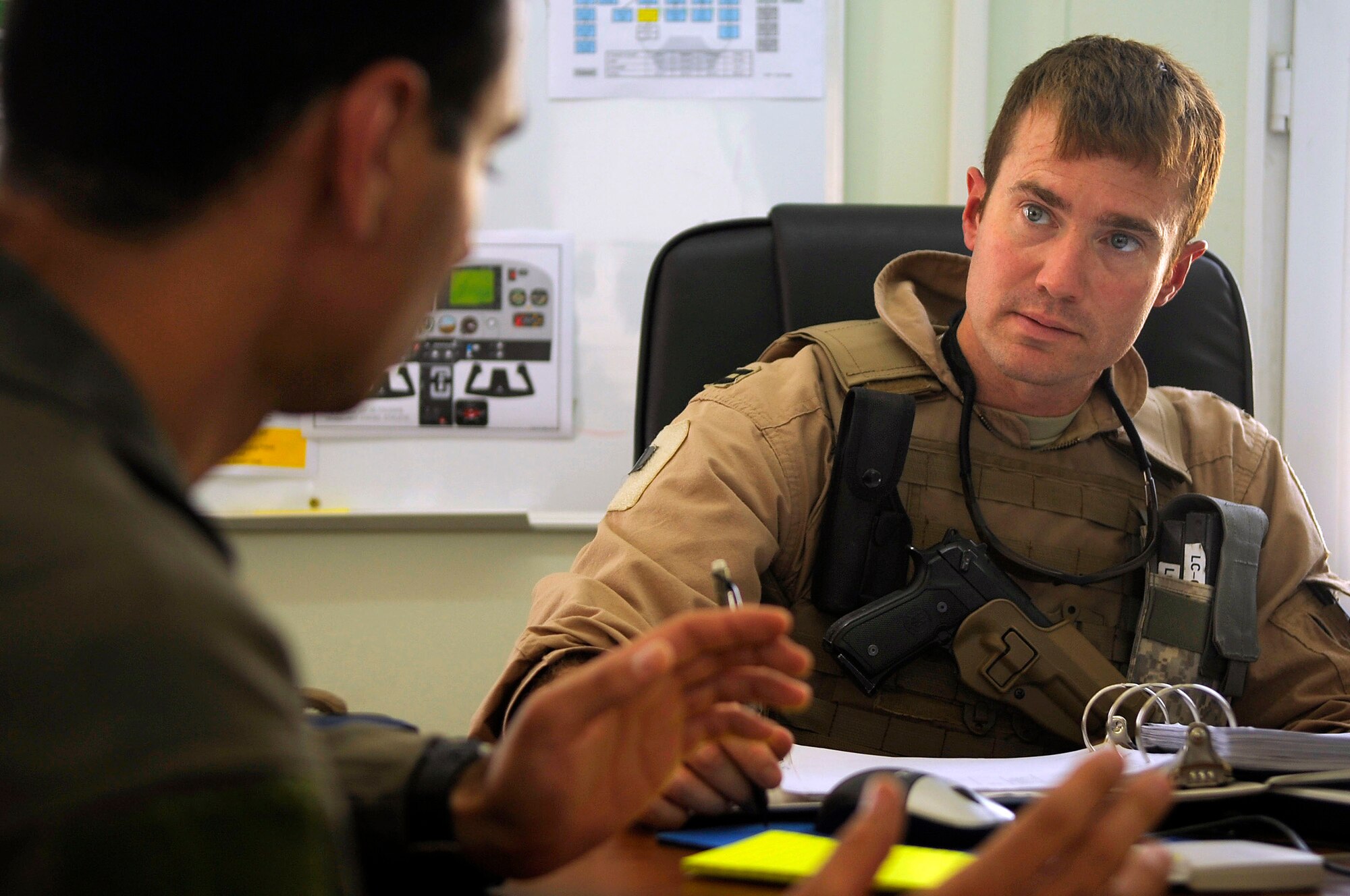 U.S. Air Force Capt. Brian Riggle, right, with the 52nd Expeditionary Flying Training Squadron at Forward Operating Base Warrior, Kirkuk, Iraq, debriefs an Iraqi air force student pilot after a transition flight. Captain Riggle is part of the team rebuilding the Iraqi air force flight training program. He is deployed from the 32nd Flying Training Squadron at Vance AFB, Okla. (U.S. Air Force photo)