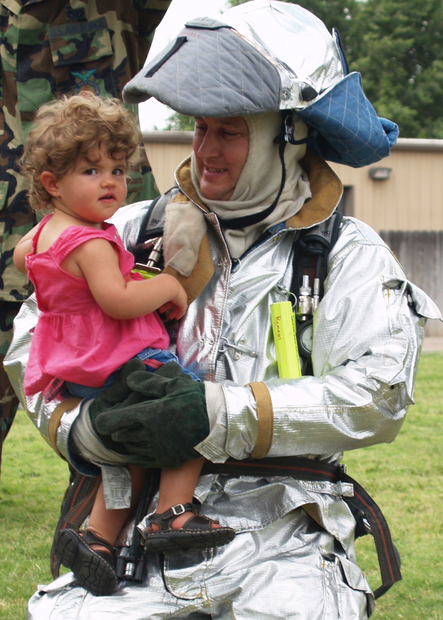 CANNON AIR FORCE BASE, N.M. -- Maj. Andrew Young, 27th Special Operations Component Maintenace Squadron, holds his daughter, Elizabeth, during a squadron picnic July 26. The major won the putting on the firefighters' equipment contest, one of many activities during the day. The fire department provided a vehicle for the children to climb on and inspect. (Courtesy photo)          