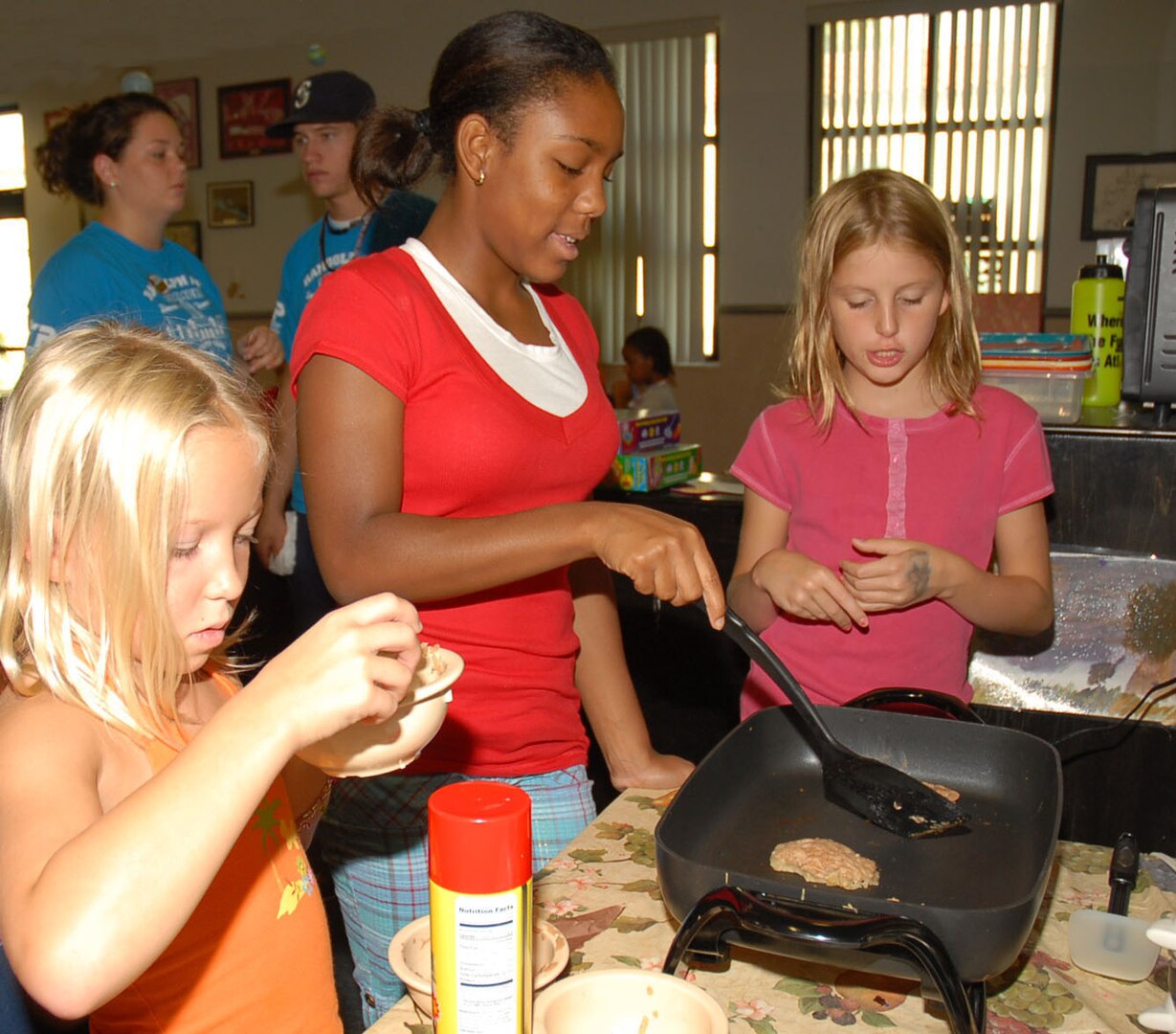 Dakota Timmermann (from left), 9, Shaitia Martin, 12, and Courtney Altemus, 10, make hashbrowns in a skillet during a cooking class at the Randolph Youth Center Aug. 6. (Photo by Thomas Warner)