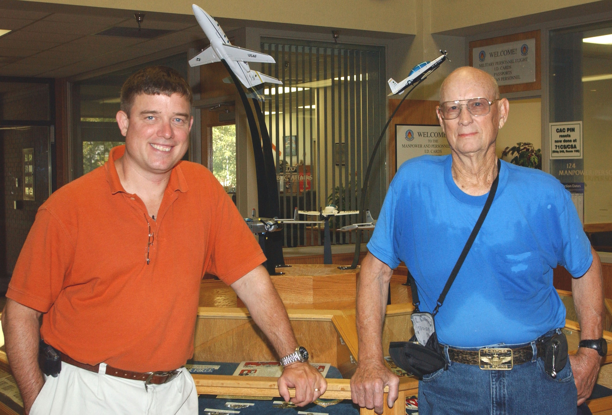 Jim Malachowski, 71st FTW historian (left) and Lonnie Gillespie, a retired Air Force Master Sergeant, stand in front of the circular display case in the lobby of Building 500 at Vance AFB, Okla. On top of the display case are nine of eleven model planes representing the aviation history of Vance. The last two planes' addition will be the culmination of a 10 year project. (U.S. Air Force photo by Stephen M. Fuller) 
